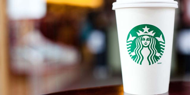 "Halifax, Nova Scotia, Anada - 18 de septiembre de 2011: Grande Starbucks va por una taza sentada en una mesa.  Starbucks es una franquicia internacional de cafeterías muy popular con más de 15 000 ubicaciones en 50 países."