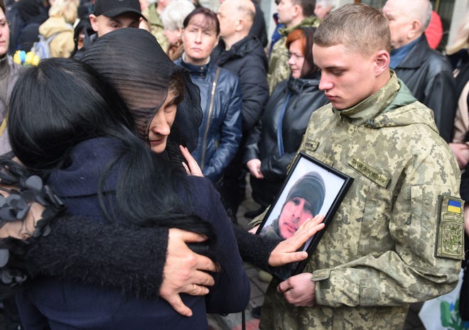 Los familiares abrazan el funeral del soldado ucraniano Theodore Osadchy en el cementerio de Lychakiv en Lviv, Ucrania occidental, el 29 de marzo de 2022.
