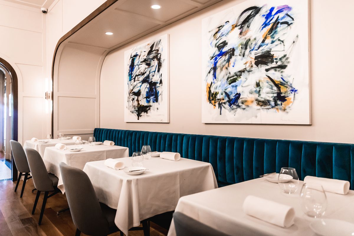 Comedor sencillo y elegante con cuadros abstractos azules en la pared.