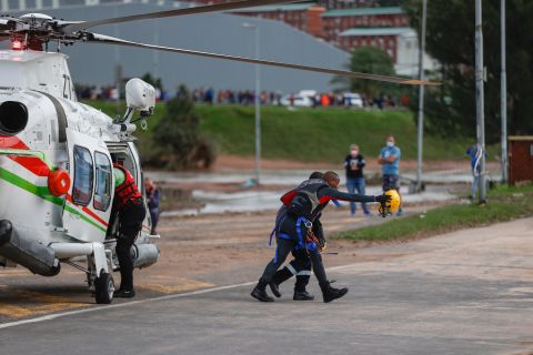 Un rescatista camina con un hombre que ha sido ayudado desde un lugar de trabajo inundado cerca de Umlazi, Sudáfrica, el 12 de abril.