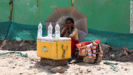 Una niña que vende agua usa un paraguas para protegerse de los rayos del sol en Nueva Delhi.