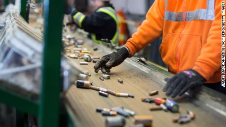 Los empleados clasifican las baterías que se mueven a lo largo de una cinta transportadora en una instalación de reciclaje.