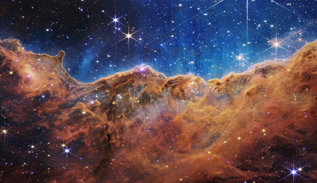 La nebulosa de Carina: las estrellas brillan contra un fondo índigo sobre nubes de gas de bronce oxidado