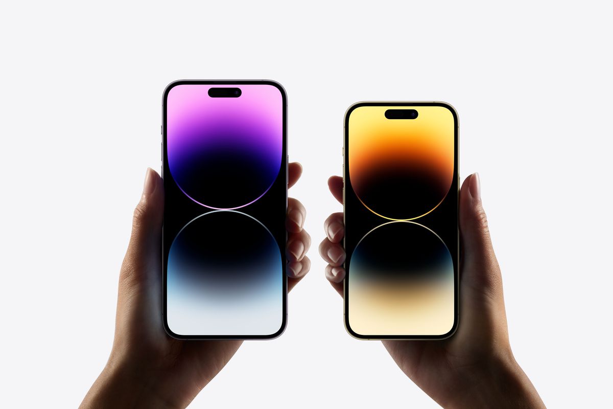 El iPhone 14 Pro y el iPhone 14 Pro Max se mantienen uno al lado del otro, sus pantallas muestran un fondo colorido.