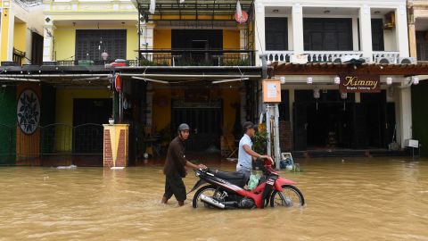La gente empuja una motocicleta en una calle inundada en la ciudad de Hoi An, provincia de Quang Nam, el 28 de septiembre de 2022.
